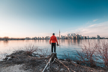 Man with a red jacket standing and facing the Toronto city skyline at Ontario, Canada