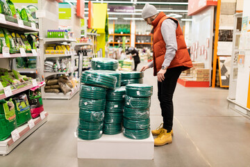 a man in a garden hypermarket is selected Come on a hose for watering work