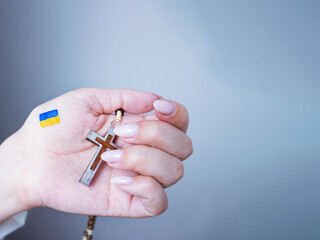 Ukrainian flag is painted on a hand holding a Christian rosary, a prayer for peace,prayer for peace