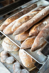Finished French bread in the bakery on the racks. Baguettes, rustic bread, crown of kings Bordeaux. Vertical photo.