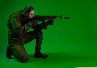 soldier in the studio on a green background with colored light. a man in military uniform with a gun, rifle or machine gun. military. airball player
