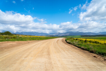 Fototapeta na wymiar farm road, dirt track with endless viewpoint towards mountains on a winter day in the Western Cape, South Africa