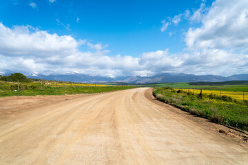 Fototapeta premium farm road, dirt track with endless viewpoint towards mountains on a winter day in the Western Cape, South Africa