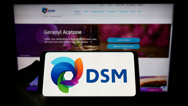 Stuttgart, Germany - 07-24-2022: Person holding mobile phone with logo of Dutch chemicals company Koninklijke DSM N.V. on screen in front of web page. Focus on phone display.