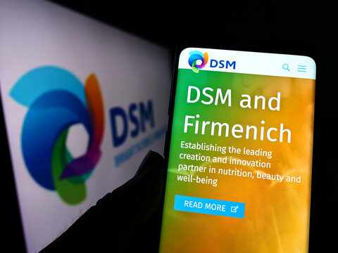 Stuttgart, Germany - 07-24-2022: Person holding cellphone with website of Dutch chemicals company Koninklijke DSM N.V. on screen with logo. Focus on center of phone display.