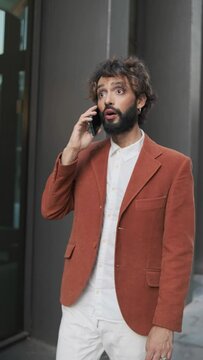 Stylish businessman talking on the phone while walking on the street in the financial district. lgbti concept.