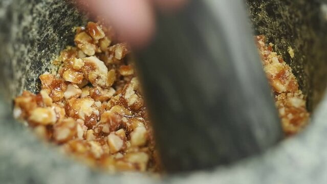 The confectioner crushing hazelnut croquant in a stone mortar.
