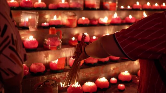Close up the hand of chinese devotees burn the incense joss stick with lotus candle