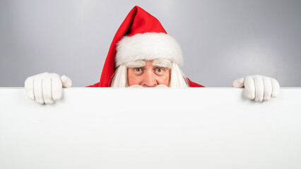 Santa Claus peeks out from behind an ad on a white background. Merry Christmas.
