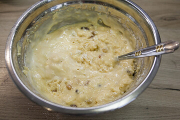Kneading dough on a muffin or cake with raisins. Metal bowl with dough and spoon. Dough preparation for cake and bakery. Step for making muffins, pie, biscuit. Baking process step by step.
