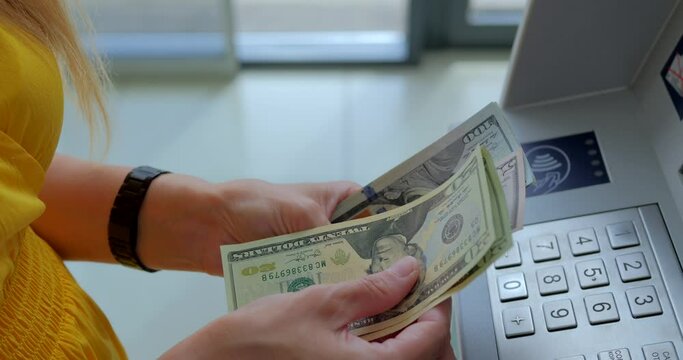 Woman counting us dollars near ATM machine 