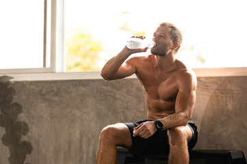 caucasian athlete man person drink a bottle of fresh water after workout in sport gym, adult male...