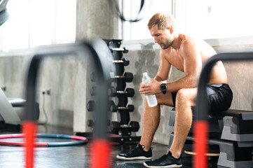caucasian athlete man person drink a bottle of fresh water after workout in sport gym, adult male...