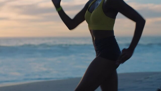Active, healthy and fit woman running on a beach at sunset looking focused, serious and determined outside at dusk. Young female exercising and training outside near the ocean against cloudy horizon