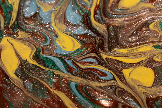 Abstract background of mixed shades of nail polish with a shiny marble pattern. Liquid colorful paint background creative brown bronze with shimmer, brown, yellow, green and blue