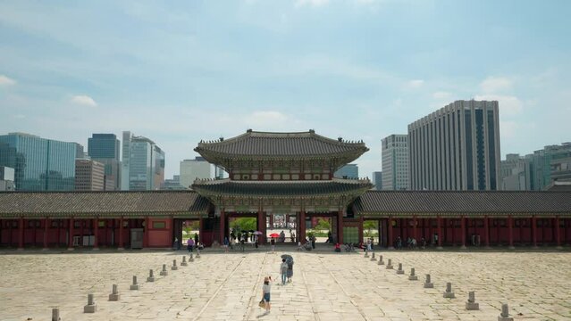 Geunjeongmun Gate of Gyeongbokgung Palace  with Tourists Entering Geunjeongjeon Hall Block on Summer Day against Seoul Office Buildings