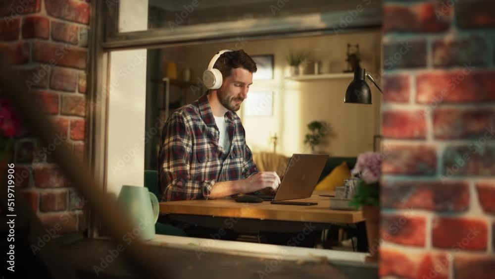 Poster handsome caucasian man working on laptop computer while sitting behind his desk at home office. free