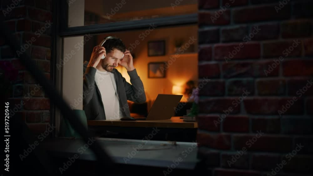 Poster Professional Tireless Software Developer Stretches and Continues to Work on Laptop, Writing Code and Working on the Project. Remote Job at Home Concept. View From Outdoors into Window. Static Shot.