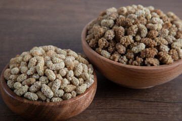 Bowl full of dried mulberry on a wooden background