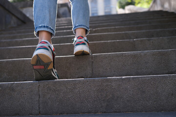 Woman wearing jeans and sneakers going up steep stairs