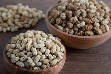 Bowl full of dried mulberry on a wooden background