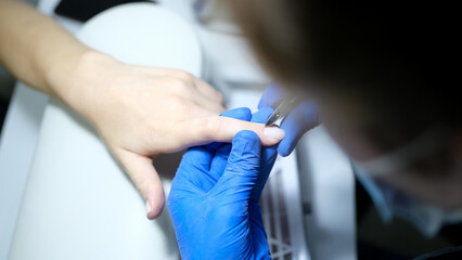 Manicurist specialist doing hardware manicure to client using special tools