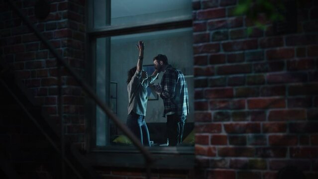 Aggressive Wife and Husband Fighting and Screaming at Each Other. Couple Quarrelling. Man and Woman Shouting And Gesturing. Scandal, Family Crisis Concept. Through Apartment Window Slow Motion Shot.