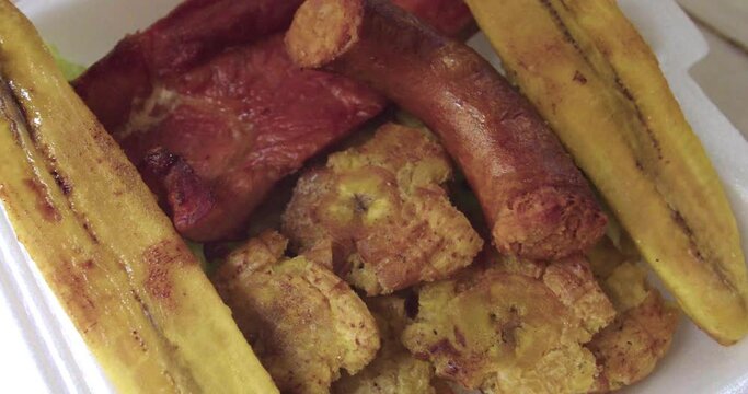 closeup of a Peruvian plate of patacones, fried ripe plantain, cecina and chorizo.