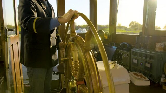 close up of a captain pulling the stearing wheel during golden hour