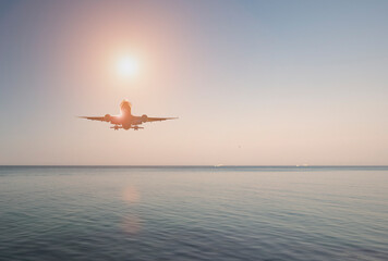 Passenger plane over the sea at sunset. Evening sea landscape. Airliner in the sky