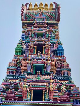Hindu temple in Tamilnadu, India. Tower with painted God sculptures against blue color sky background.