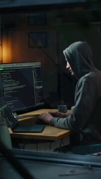 Vertical Screen: Night Apartment: Evil Greedy Hacker wearing Hoodie Breaks into Data Servers, Does DDOS Attack, Phishing Scheme, Malware, Sends Virus. Cyber Security and Cyber Crime Concept.