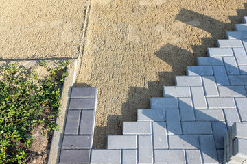 Paving the road from garden bricks by a professional paver. Laying gray concrete paving slabs on a gravel and sand base.