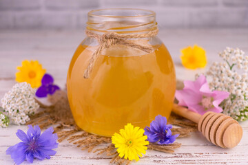 Obraz na płótnie Canvas Flower honey in a jar and fresh wildflowers.