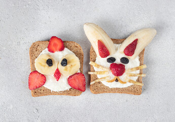 Two sweet toasts for kids in shape of chick and rabbit with strawberries, banana, cream cheese and...
