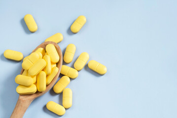 A pile of yellow pills in a wooden spoon, macro photo.