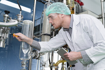 Inspector caucasian scientists use clipboard in the machine room extracting oil and cannabis seeds	