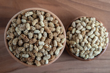 Bowl full of dried mulberry on a wooden background
