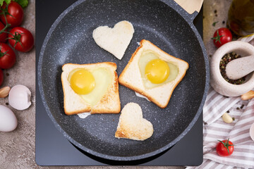 Fried egg Toasts with heart shaped holes on frying pan