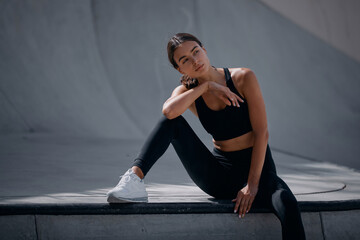 Fototapeta premium Sporty and fit woman sitting on the street, relaxing after nice workout session