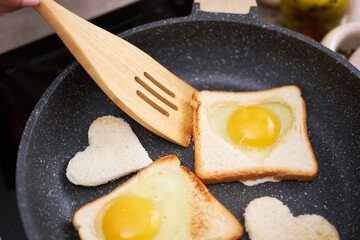 Fried egg Toasts with heart shaped holes on frying pan