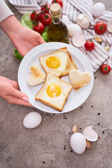 Woman pits plate with Fried Egg on Toast Bread on concrete table for Breakfast
