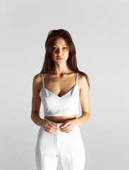 Front portrait of a young brunette woman with makeup and hairstyle, dressed in white, isolated white background.