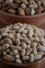 Bowl full of dried mulberry on a wooden background