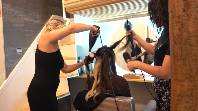 A brunette girl sitting in the beauty salon drying her hair with the dryer, hairdressing