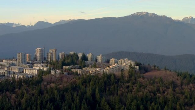 Simon Fraser University Campus Buildings On Heavy Forest Landscape Of Burnaby Mountain Peak In BC, Canada. Aerial Wide Shot