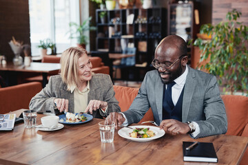 Business couple talking to each other and smiling during their business lunch at the restaurant