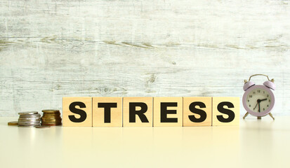 Six wooden cubes with letters are on the table next to the coins. The word is STRESS. On a gray background.