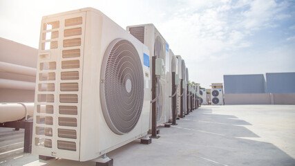 Air conditioning (HVAC) on the roof of an industrial building with blue sky and clouds.