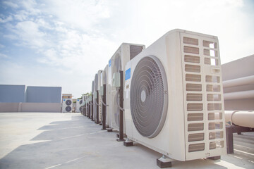 Air conditioning (HVAC) on the roof of an industrial building with blue sky and clouds.	